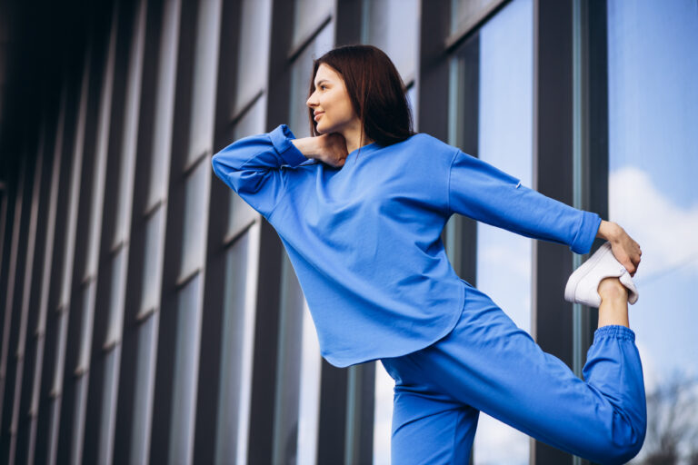 Woman in blue sports wear stretching outside the street